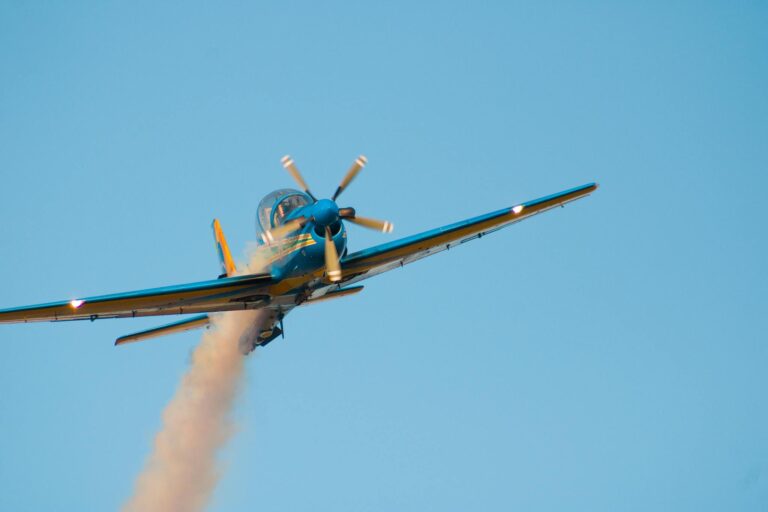 Military aircraft soaring with smoke trail on a clear blue sky background, showcasing precision flying.